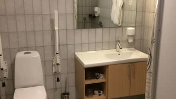 Une salle de bain comprenant des toilettes, un lavabo, un miroir et un sol carrelé.