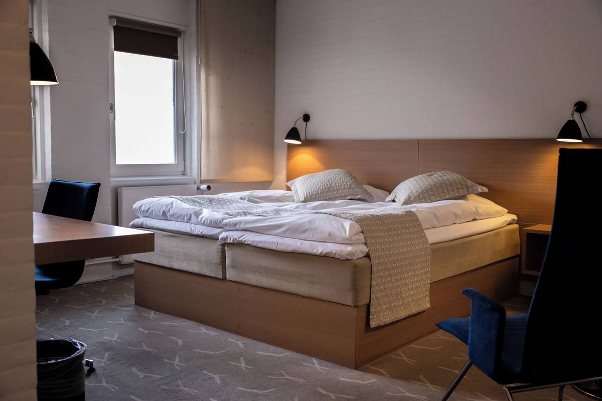 Un dormitorio moderno con cama, mesitas de noche, escritorio y una silla.