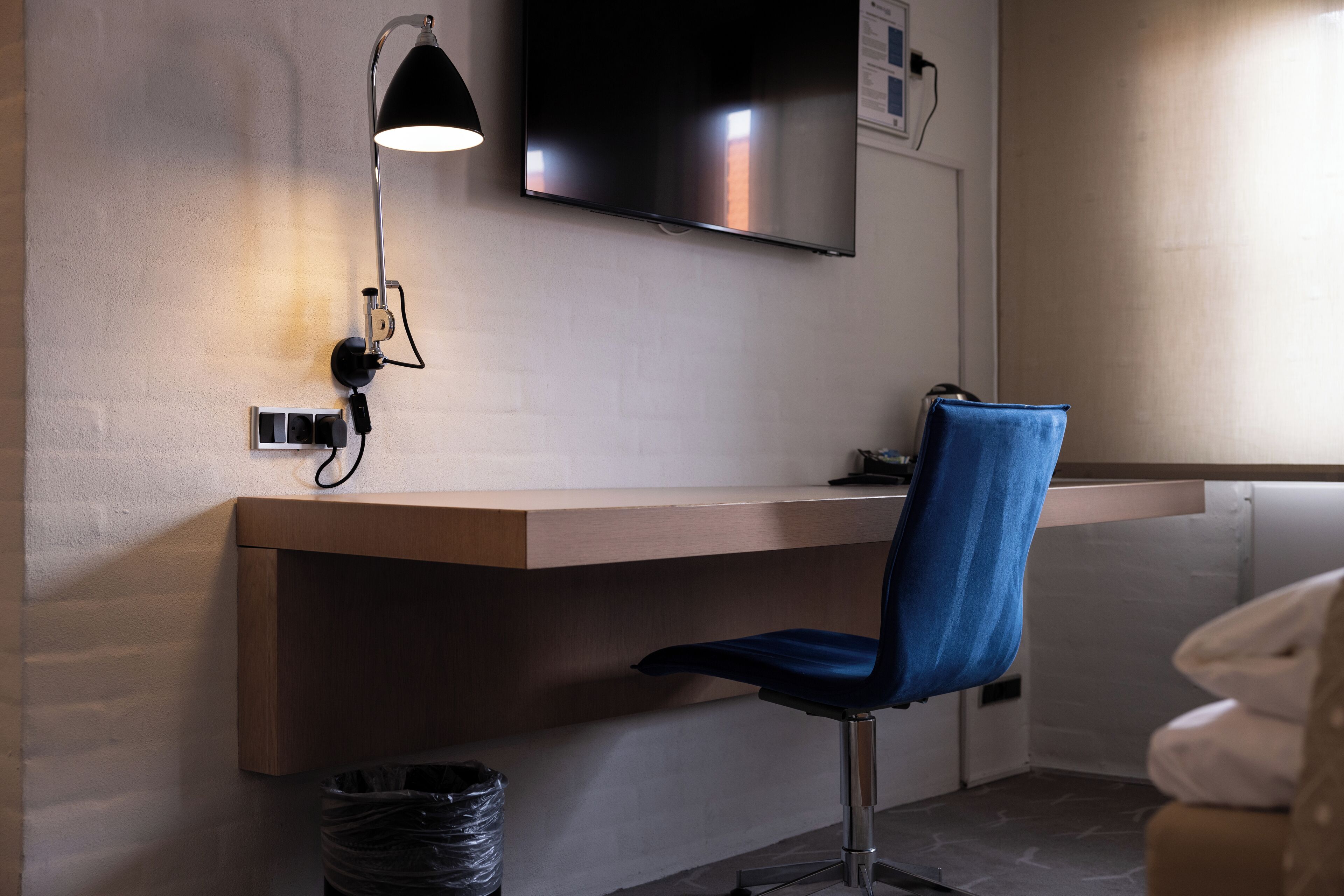 Un espacio de oficina moderno con escritorio, silla y televisor montado.