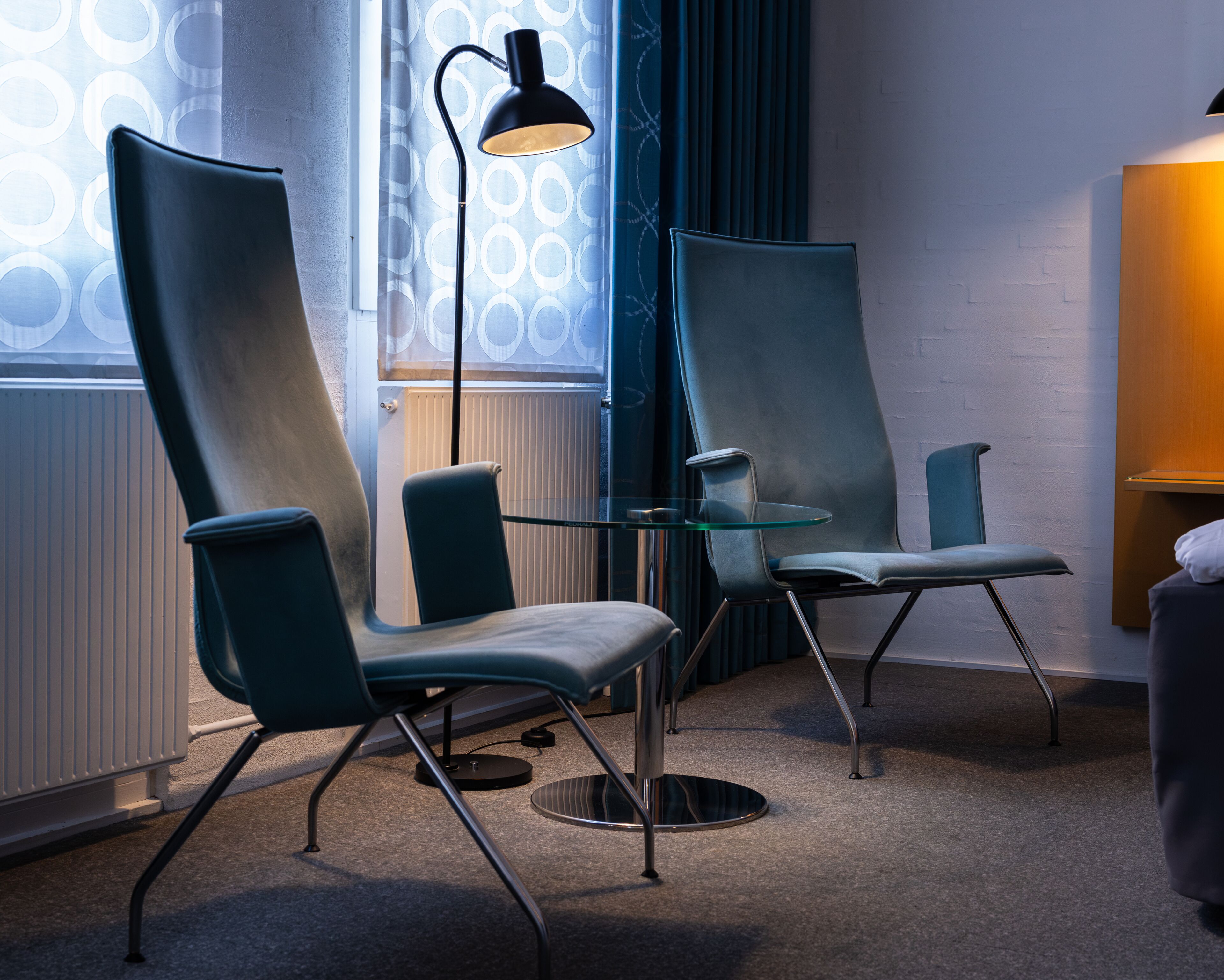 Una habitación moderna con dos sillones, una mesa de cristal y una lámpara de pie.