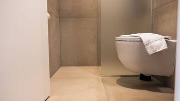 A modern bathroom with a toilet, a towel on the seat, and a tiled floor.