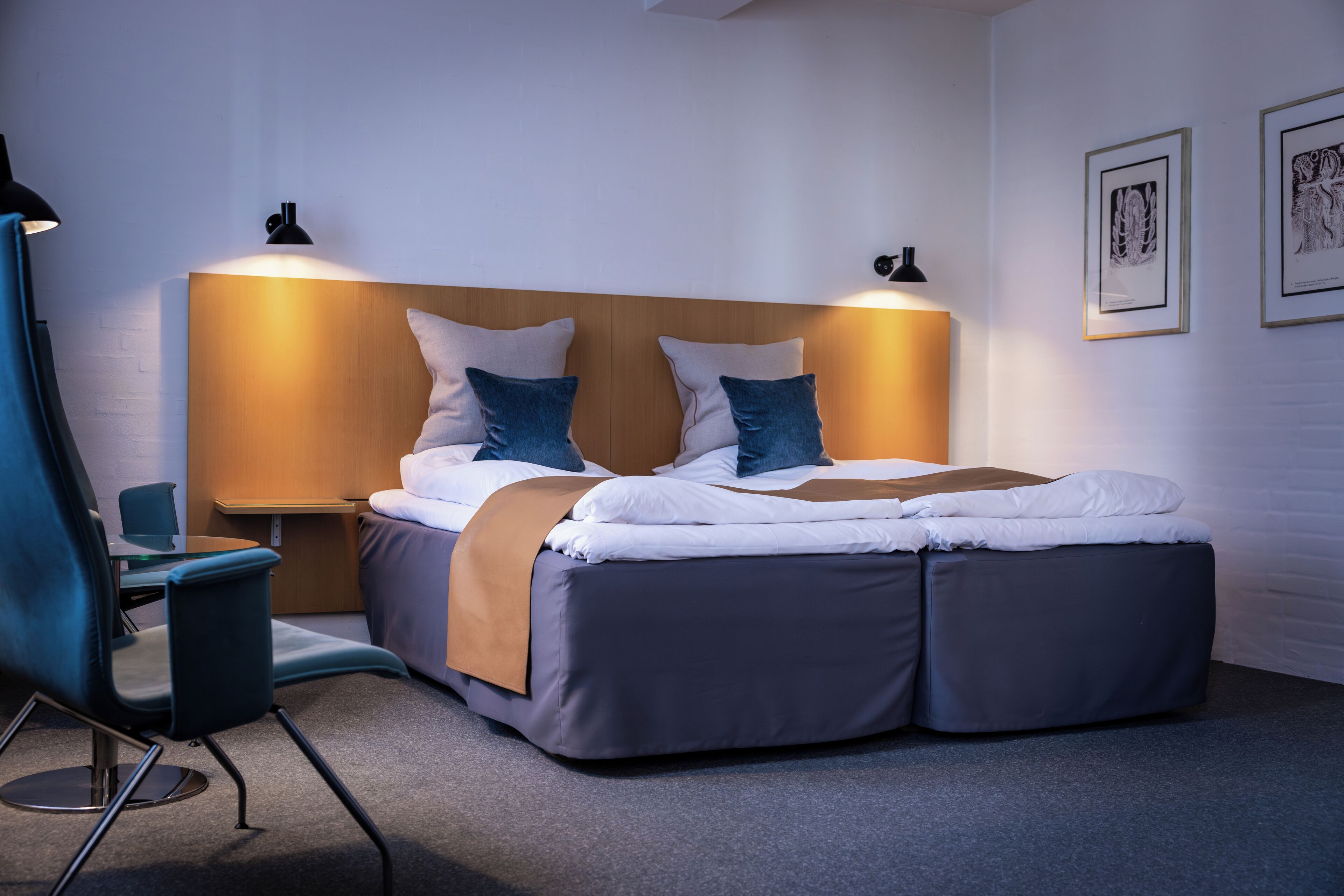A modern hotel room with a double bed, a desk, and a chair.