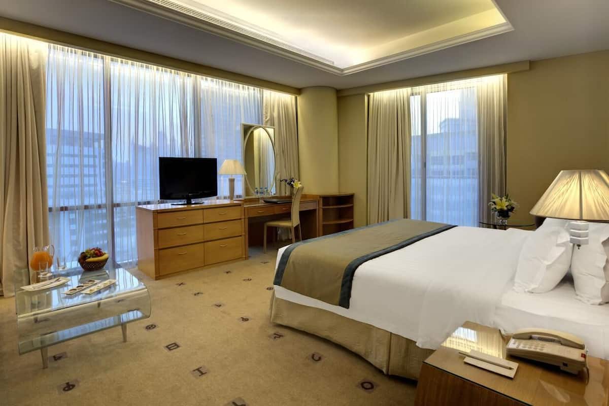 A hotel room with a bed, a desk, a television, and a window with curtains.