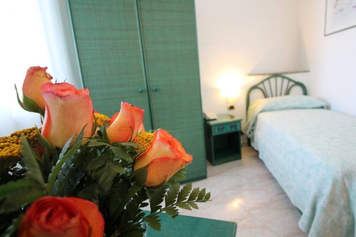 Un dormitorio con cama, mesita de noche, lámpara y armario verde.