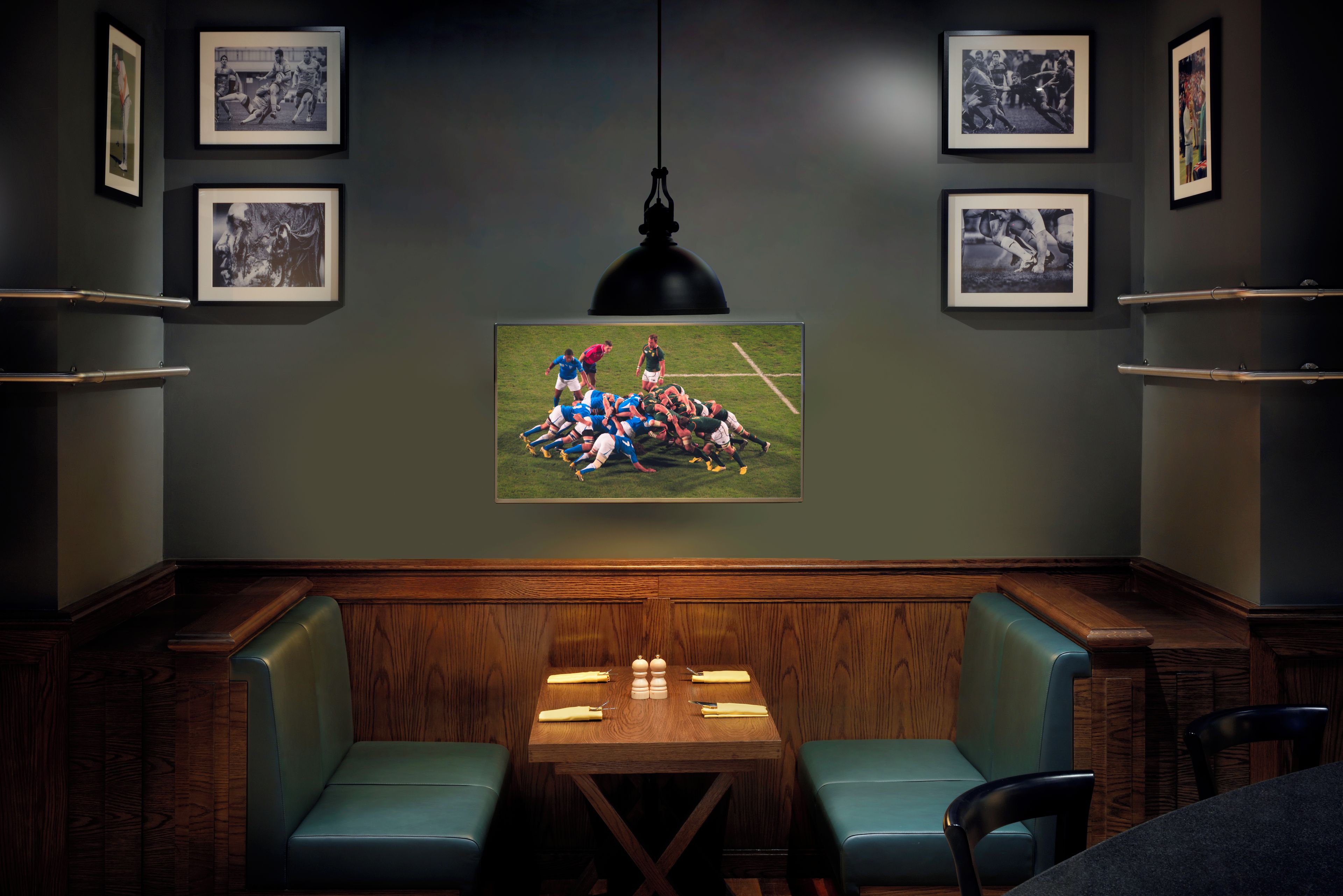 A room with a wooden table, two blue cushioned chairs, and framed photographs on the walls.