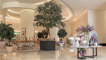 A spacious lobby with a large tree, seating areas, and a reception desk.