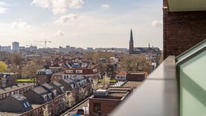 A cityscape with traditional architecture, including a prominent church spire, and residential buildings with sloped roofs. - Hampshire Delft Centre (Delft)