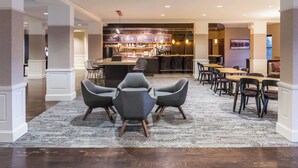 A modern dining area with a bar, bar stools, and a patterned rug.