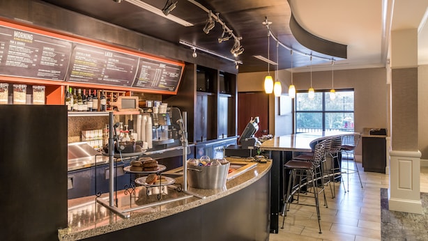 A modern bar area with a menu board, bar stools, and a countertop with various items.