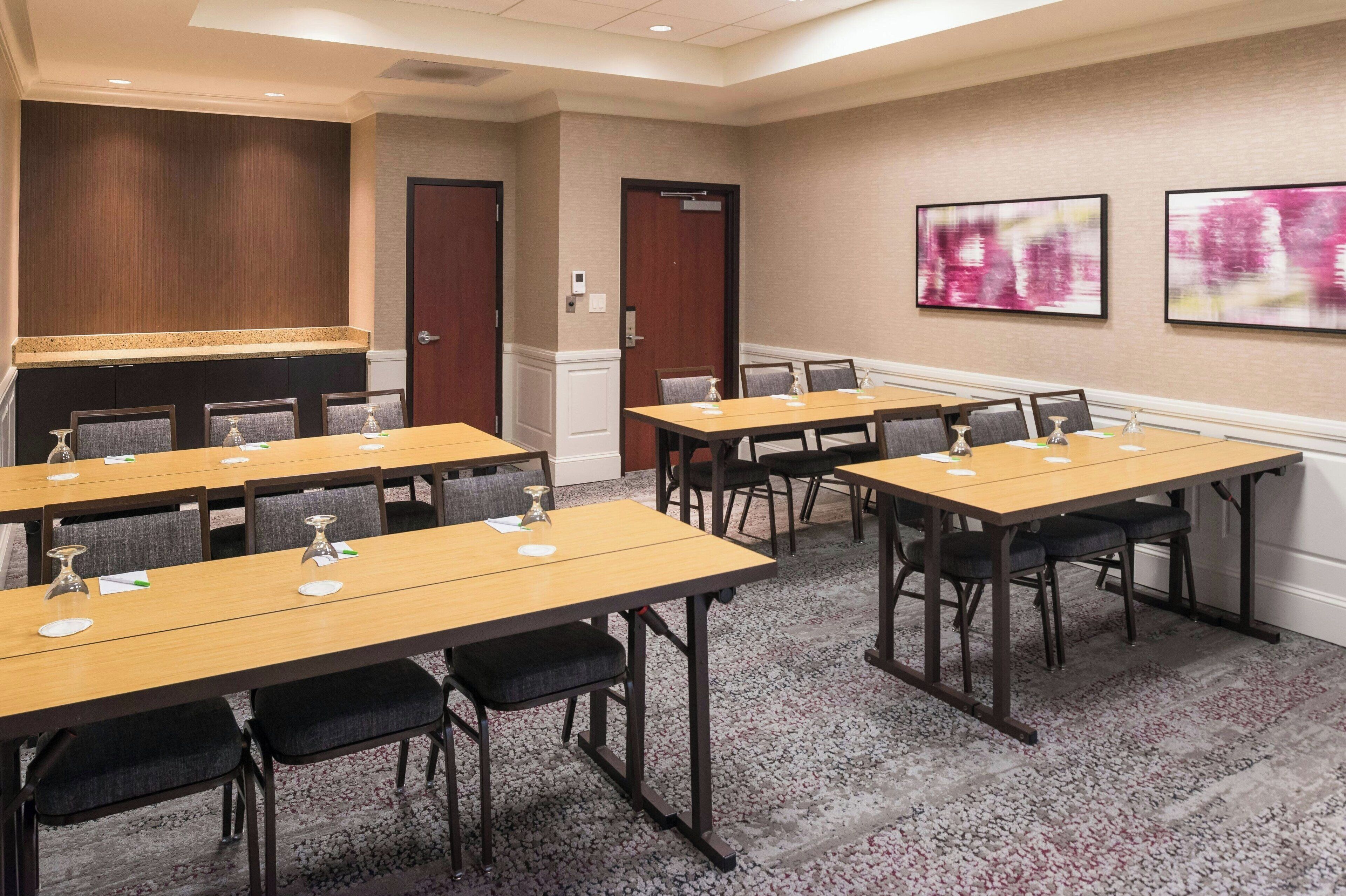 A conference room with multiple tables and chairs, equipped with nameplates and water glasses.