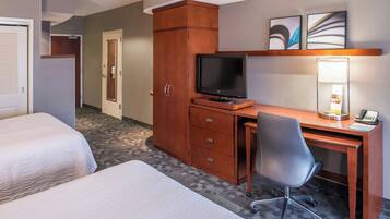 A hotel room with two beds, a desk with a computer and a lamp, a TV, and a phone.