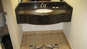 Un baño con lavamanos, espejo y baldosas de suelo estampadas.