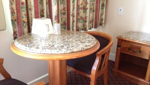 A round table with a granite top, surrounded by wooden chairs with cushioned seats. - Walls Motel Long Beach (Long Beach)