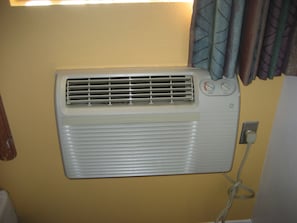 A wall-mounted air conditioner with a control panel, a power outlet, and a cable.