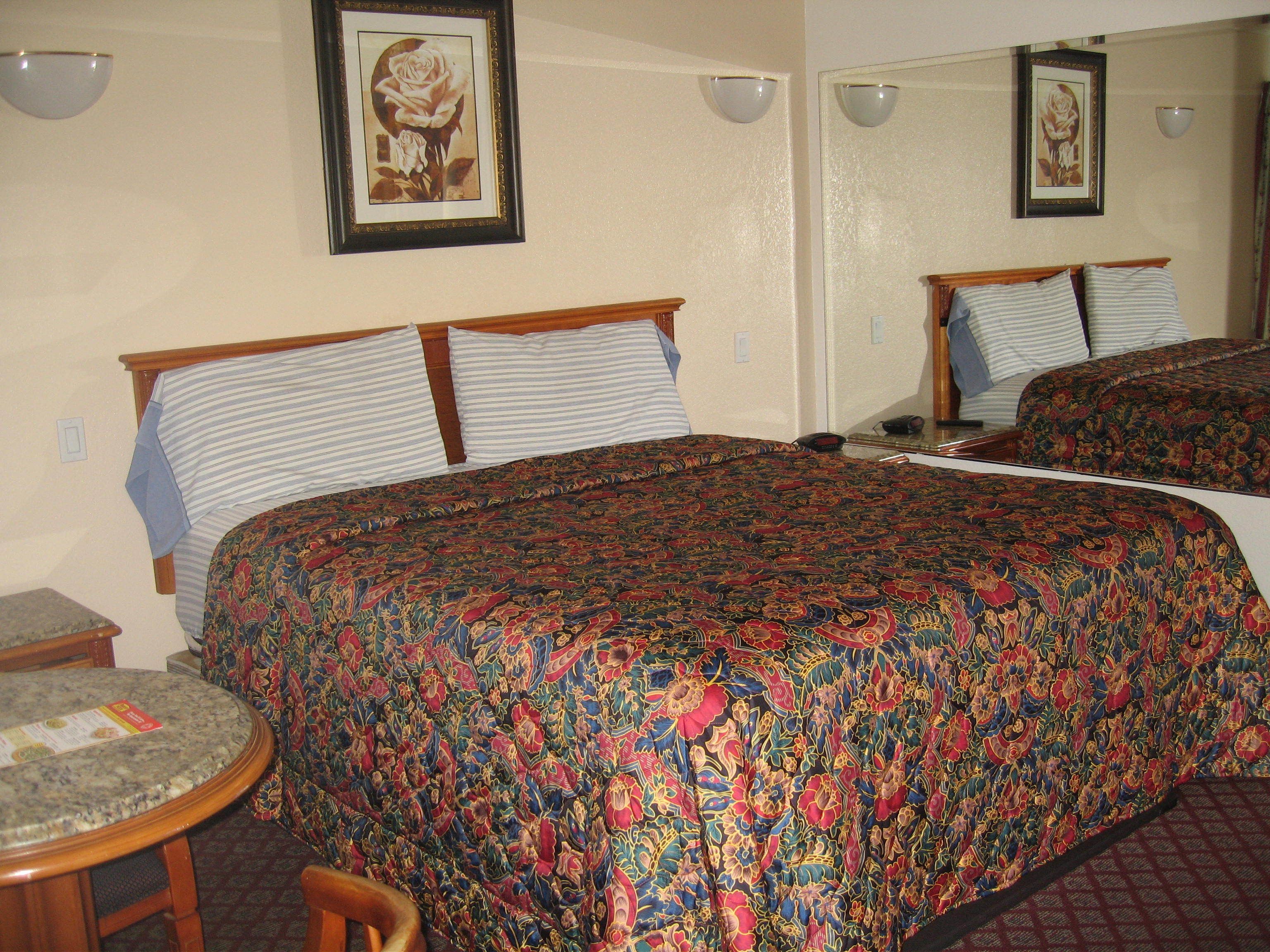 Ein Hotelzimmer mit zwei Betten, einem kleinen runden Tisch und einem Stuhl.