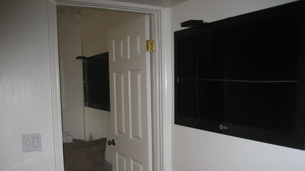 A bathroom with a white door, a mirror, and a black sink. - Walls Motel Long Beach (Long Beach)