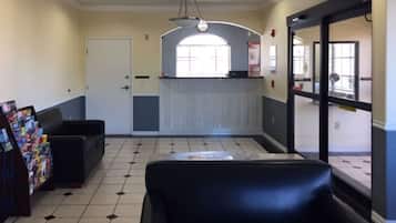 Uma área de recepção com balcão, porta e espaço de estar com revistas.
