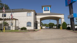 A motel with a large '6' sign, a covered entrance, and a parking lot. - Motel 6 Tyler, TX (Tyler)