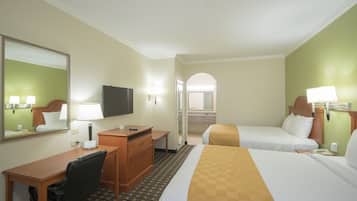 A hotel room with a bed, a desk, a chair, a television, a mirror, and a bathroom visible through an arched doorway.