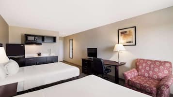 Ein Hotelzimmer mit zwei Betten, einem Schreibtisch, einem Stuhl, einem Fernseher, einer Mikrowelle und einer Lampe.