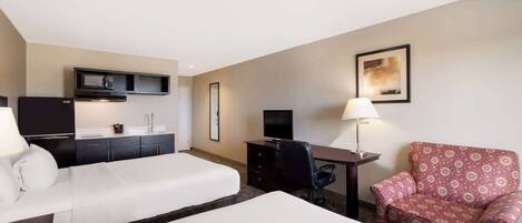 A hotel room with two beds, a desk, a chair, a TV, a microwave, and a lamp.