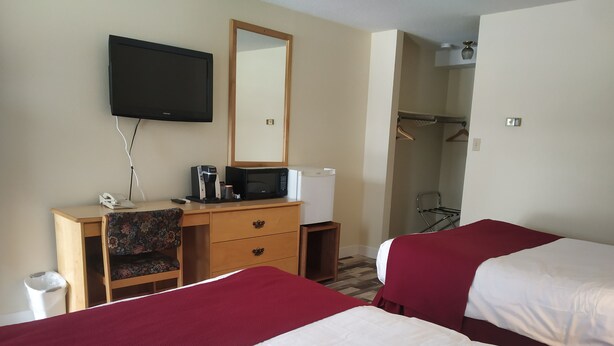 Habitación de hotel con dos camas, un escritorio, teléfono, cafetera, microondas y un espejo.