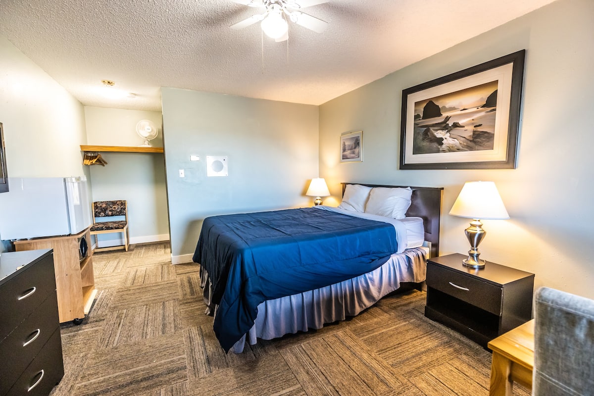 A bedroom with a bed, bedside tables, a desk, and a chair.