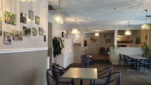 Un restaurant doté d’une salle à manger principale, d’une cuisine située à l’arrière et d’œuvres d’art murales.