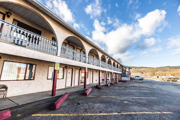 A motel with multiple balconies, a parking lot, and a mountainous backdrop. - Pleasant Valley Motel (Houston)