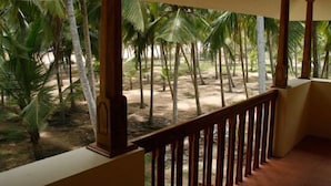 Un balcón con vista a una zona arenosa y palmeras.