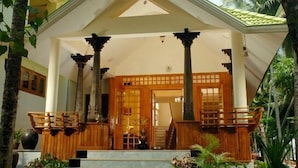 Un edificio tradicional con un porche de madera, columnas y una escalera que lleva a la entrada.