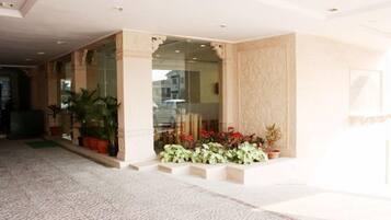 A hotel lobby with a patterned floor, a glass entrance, and potted plants.