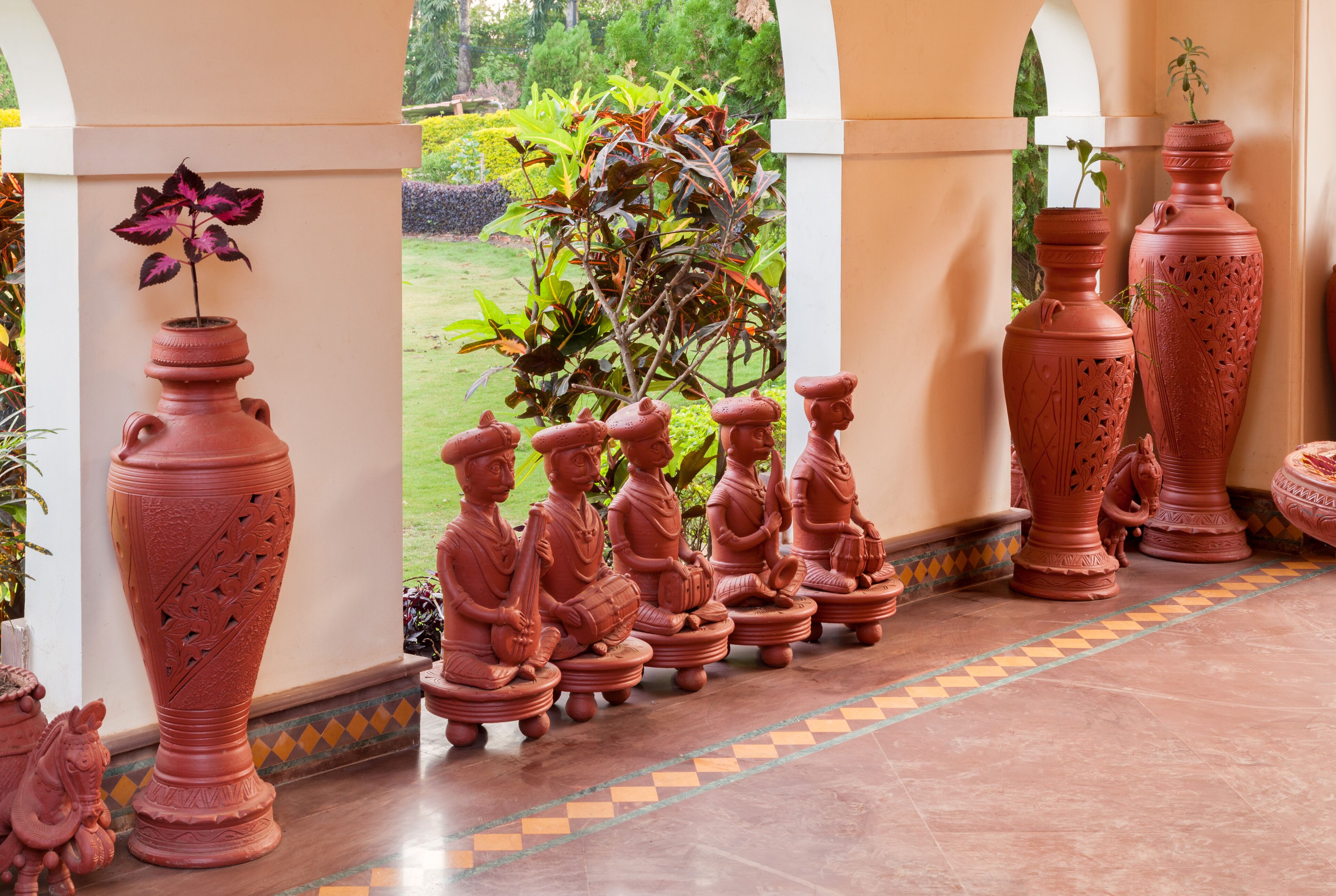Una serie de jarrones y estatuas de terracota alineados a lo largo de un camino empedrado.
