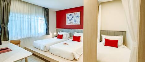Una habitación de hotel con dos camas, una mesa de comedor y una pared de acento roja.