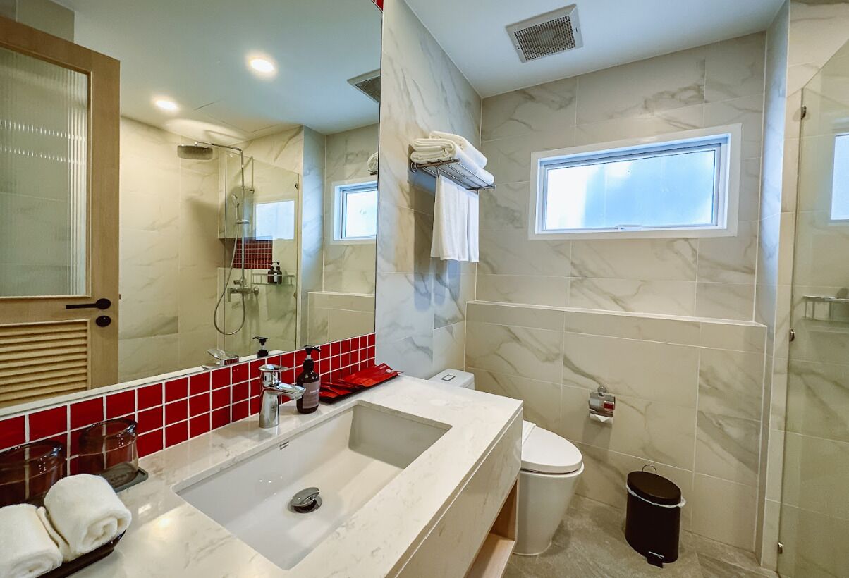 Un baño moderno con un lavamanos grande, inodoro, ducha y ventana.