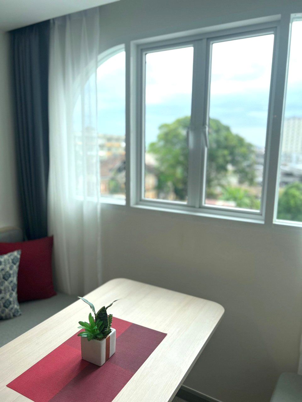 A room with a window, a small table, and a potted plant.