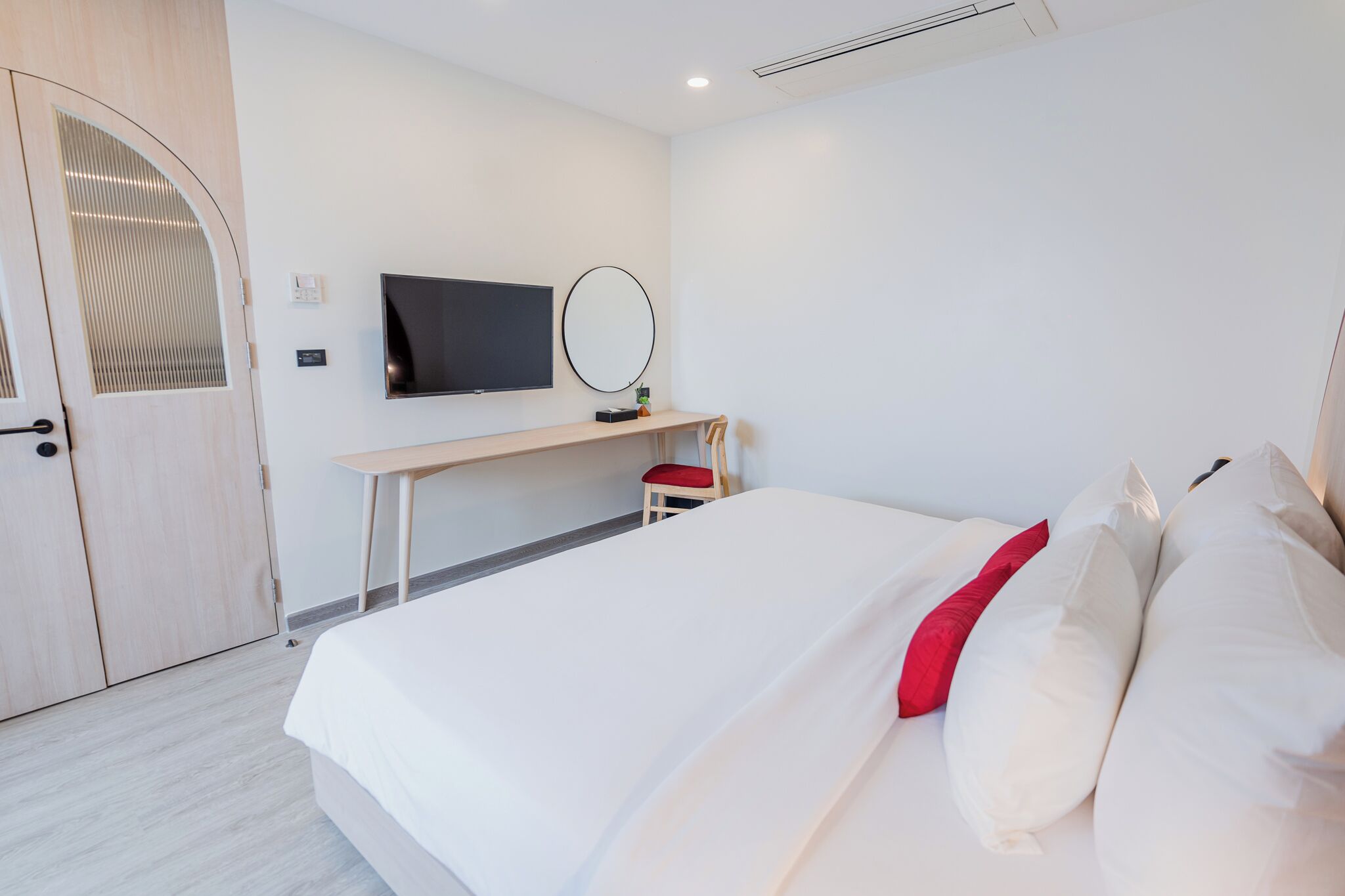 Una habitación de hotel con cama, escritorio, televisión y armario.