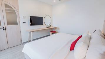 Una habitación de hotel con cama, escritorio, televisión y armario.