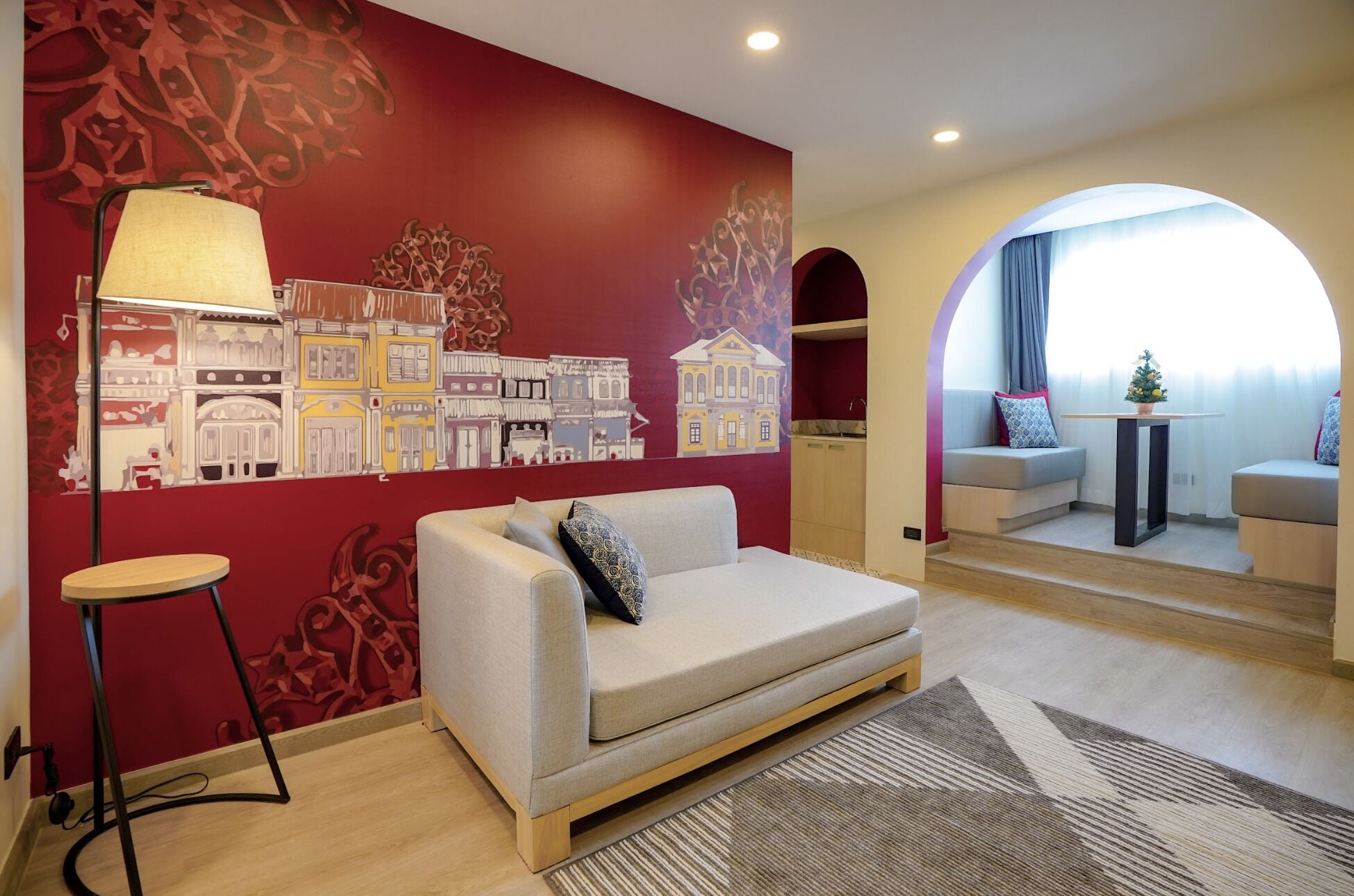 A living room with a sofa, a lamp, and a wall mural.