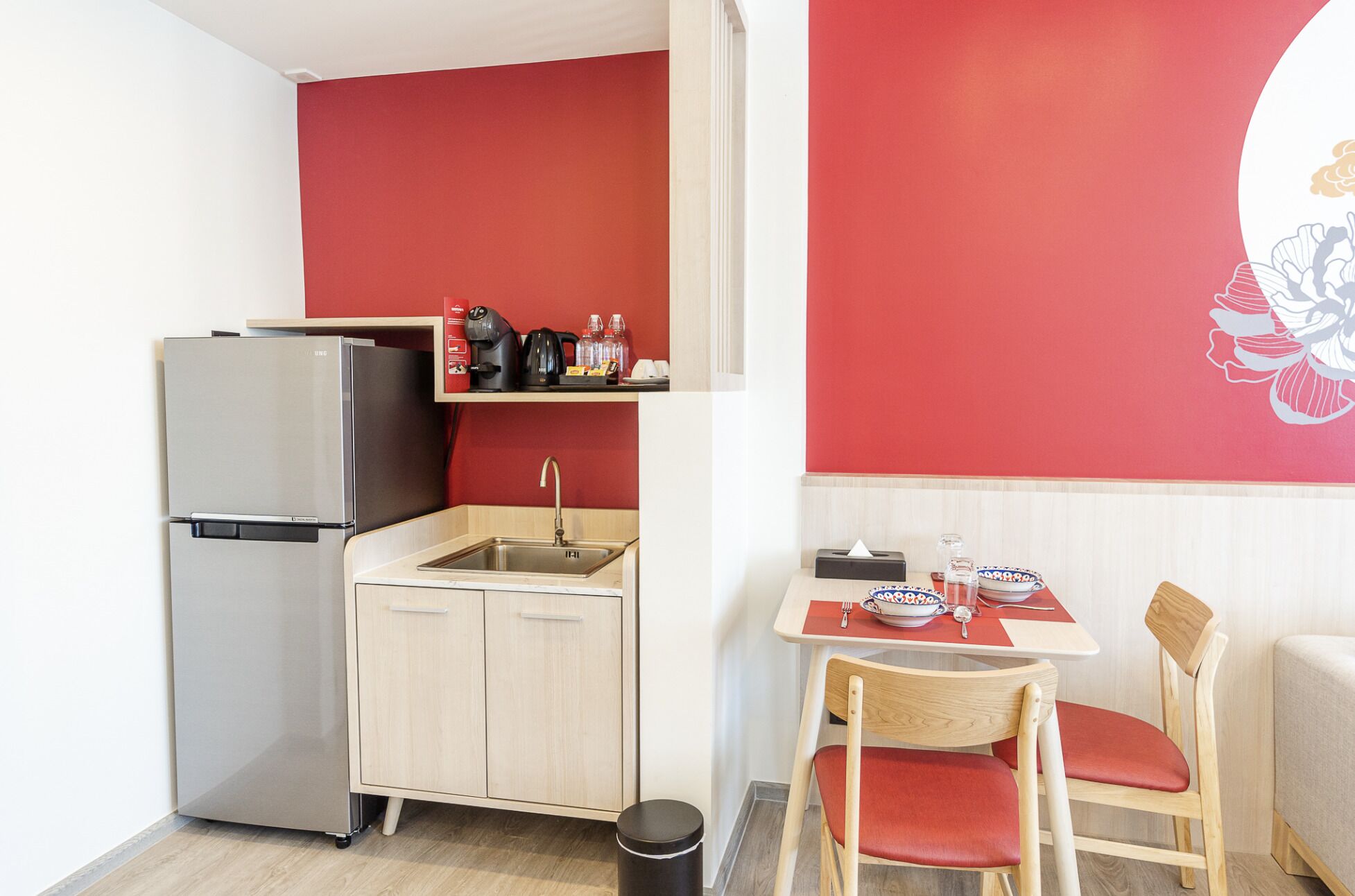 A compact kitchen with a refrigerator, sink, and a small dining area with a table and chairs.