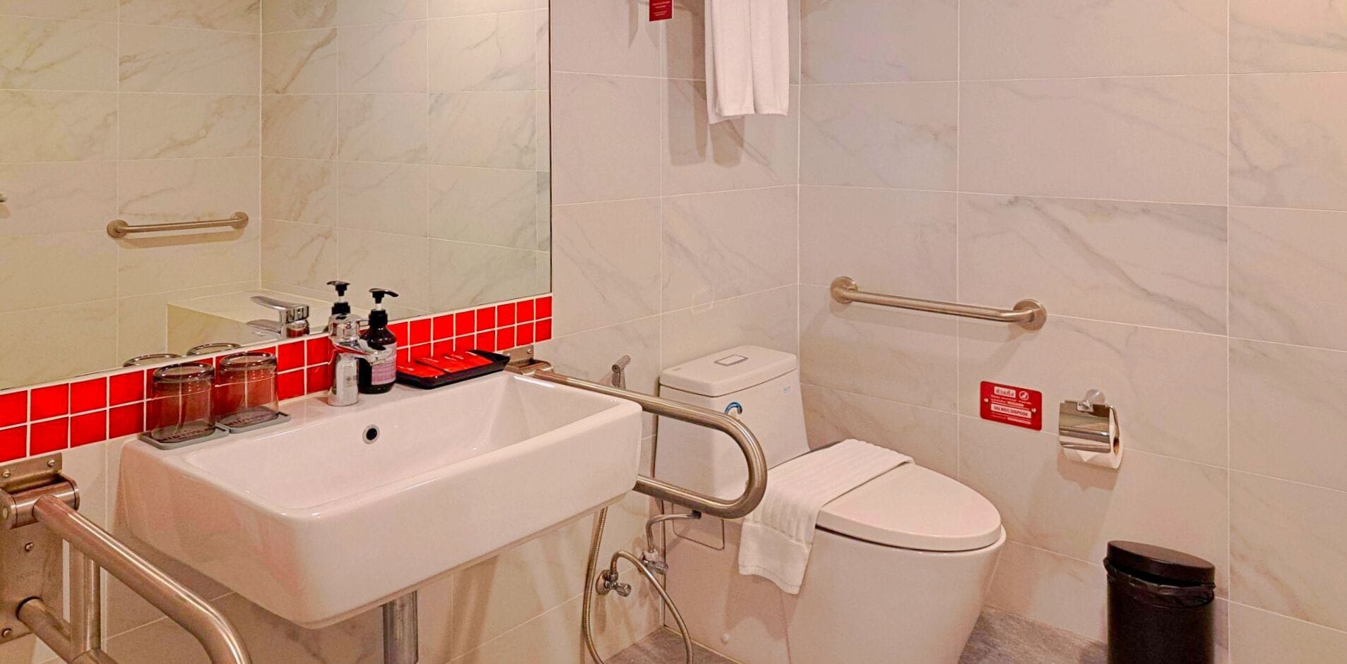 Un baño con lavamanos, inodoro y barras de apoyo.