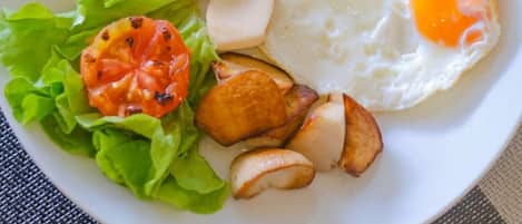 A plate with eggs, ham, sausages, lettuce, and roasted potatoes.
