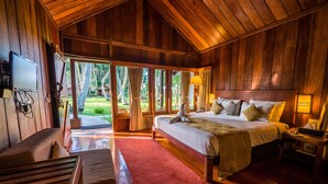 Una habitación amplia de madera con una cama grande, un banco de madera y un tapete rojo.