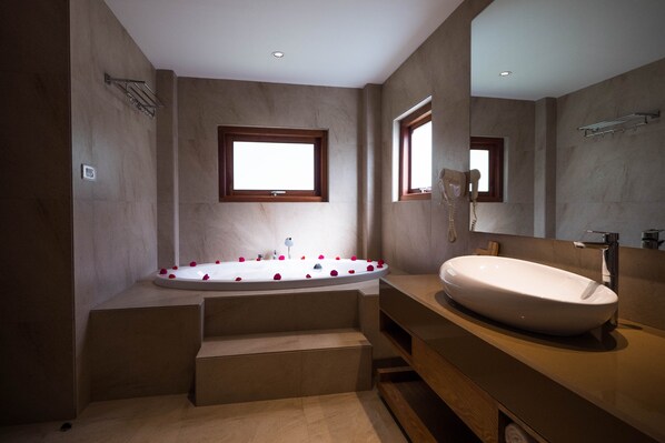 A modern bathroom with a freestanding bathtub, a large mirror, and a wooden vanity.
