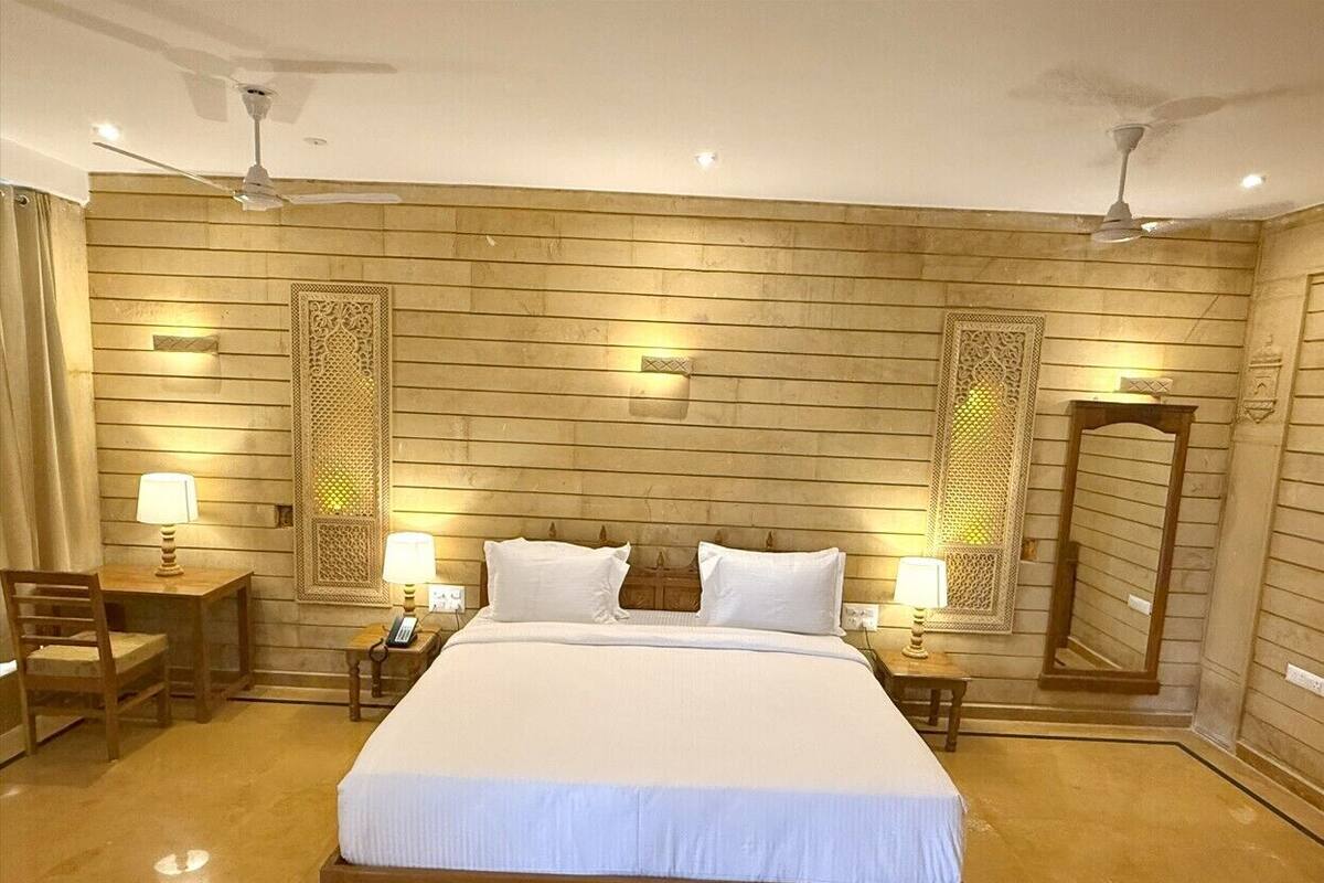 A hotel room with a large bed, two bedside tables with lamps, a chair, and a mirror on the wall.