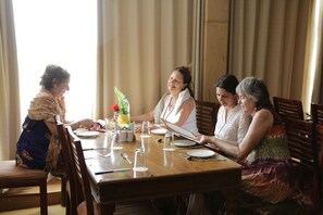 A dining table set for four people with a floral arrangement, salt and pepper shakers, and cutlery. - Hotel Golden Haveli (Jaisalmer)