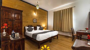 A hotel room with a wooden bed, a desk with a chair, a wardrobe, and a window with curtains.