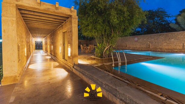 Un área de piscina con un paseo cubierto y una pared de piedra.
