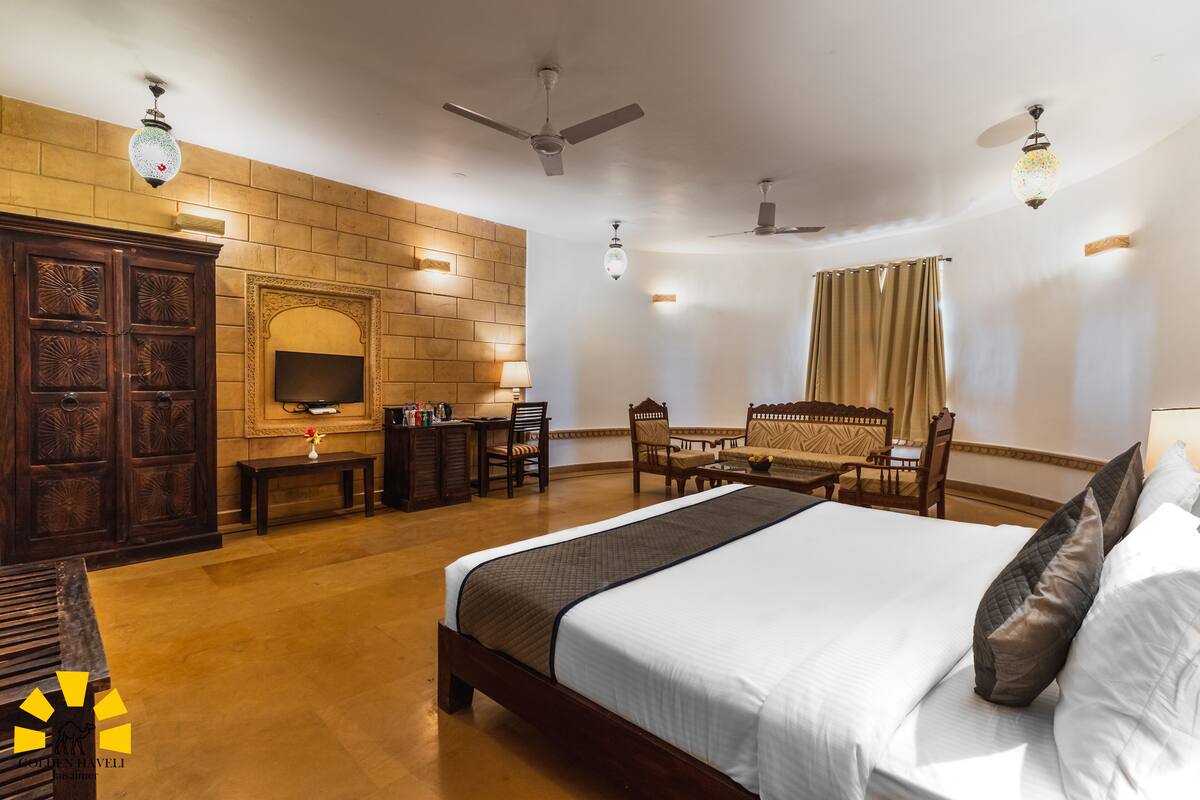 A hotel room with a large bed, wooden furniture, a TV, and a fireplace.