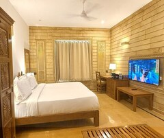 Habitación de hotel con una cama grande, un escritorio con silla, un televisor y una ventana con cortinas.